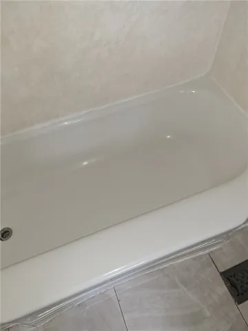 A classic soaking tub anchors the bathroom alongside neutral tiled flooring.