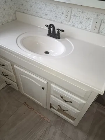An integrated solid surface sink vanity stands out against patterned wall accents and tile flooring.