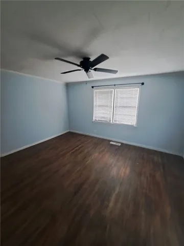 Rich hardwood flooring anchors this versatile bedroom space filled with natural light.