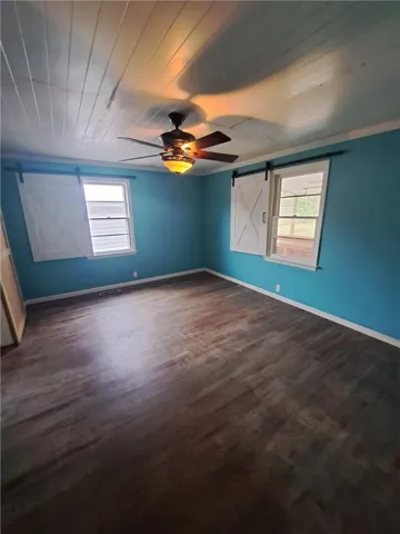Rustic sliding shutters and detailed wood panel ceilings add custom character to this bedroom.