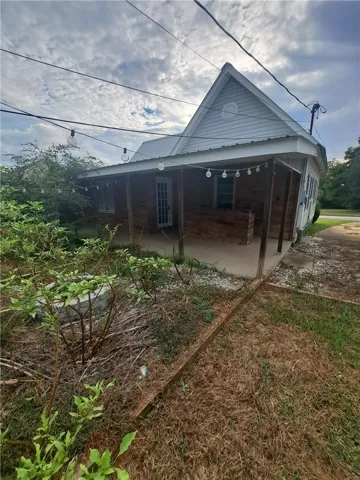 A spacious covered porch offers a sheltered outdoor space overlooking the yard.