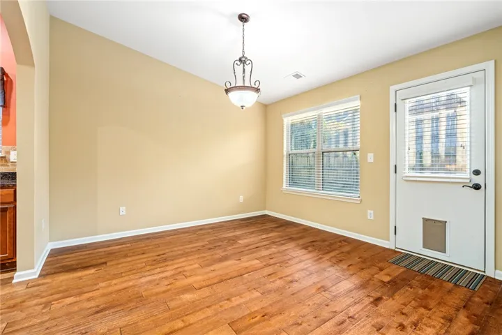 Rich hardwood flooring complements the high ceilings and elegant hanging light fixture in this dining area.