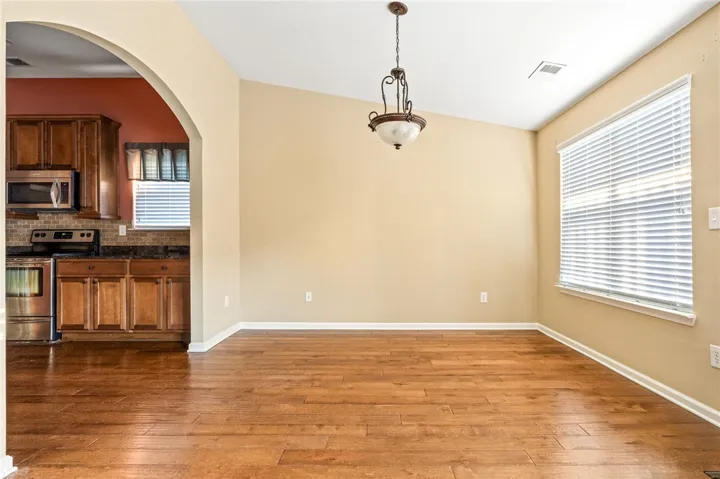 An arched doorway connects the warm wood-floored dining area directly to the kitchen.