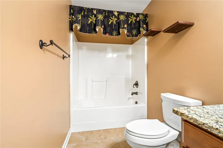 Warm wall tones complement the tile flooring and stone vanity counter in this functional bathroom.