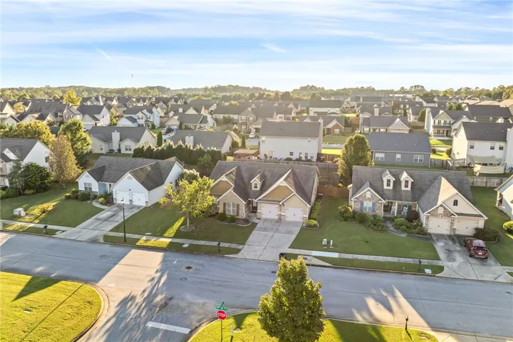 An aerial view showcases a quiet suburban neighborhood lined with manicured lawns and paved driveways.