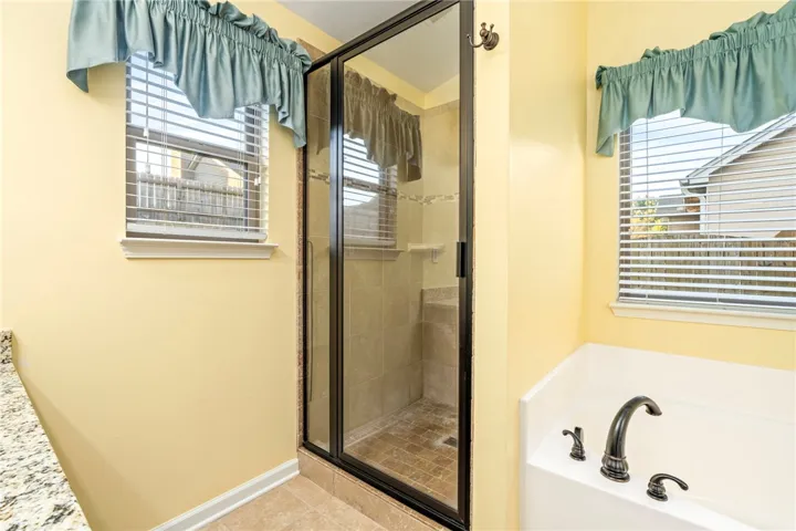 Natural light pours over the soaking tub and glass-enclosed walk-in shower.