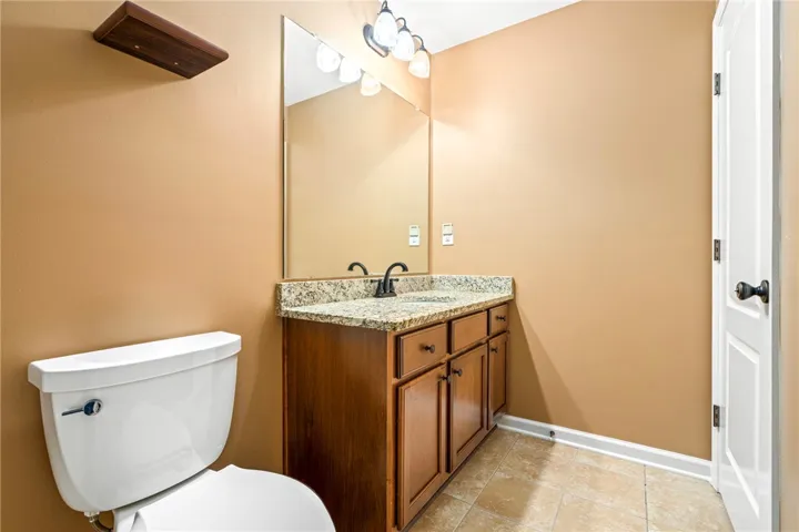 Rich wood cabinetry and speckled stone counters ground this classic washroom design.