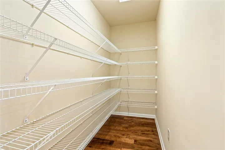 Ample wire shelving lines this walk-in storage area featuring warm wood-look flooring.