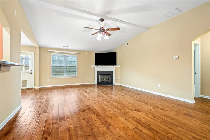 Rich hardwood floors sweep across this airy living space anchored by a corner fireplace.