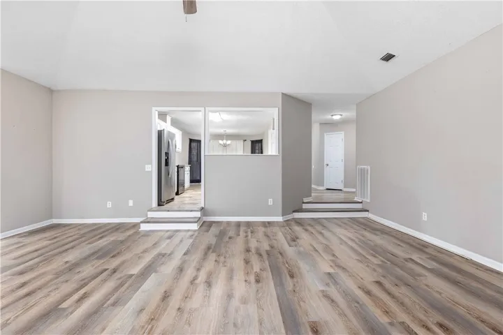 Gleaming wood-look floors complement the vaulted ceiling in this spacious, open-concept living area.