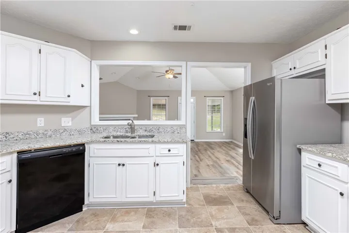 Stone countertops and white cabinetry define this kitchen overlooking the adjoining living areas.