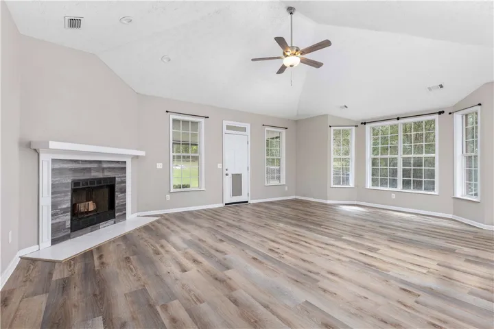 A spacious living area features vaulted ceilings, durable wood-look flooring, and a modern tiled fireplace.