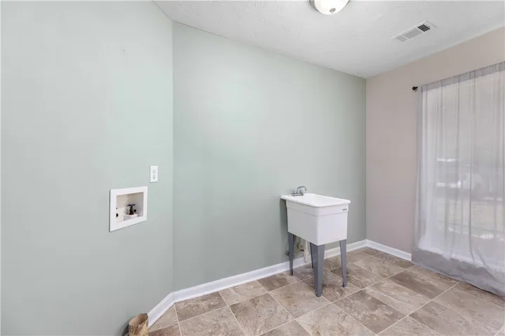 Tiled flooring and a utility sink define this functional dedicated laundry space.