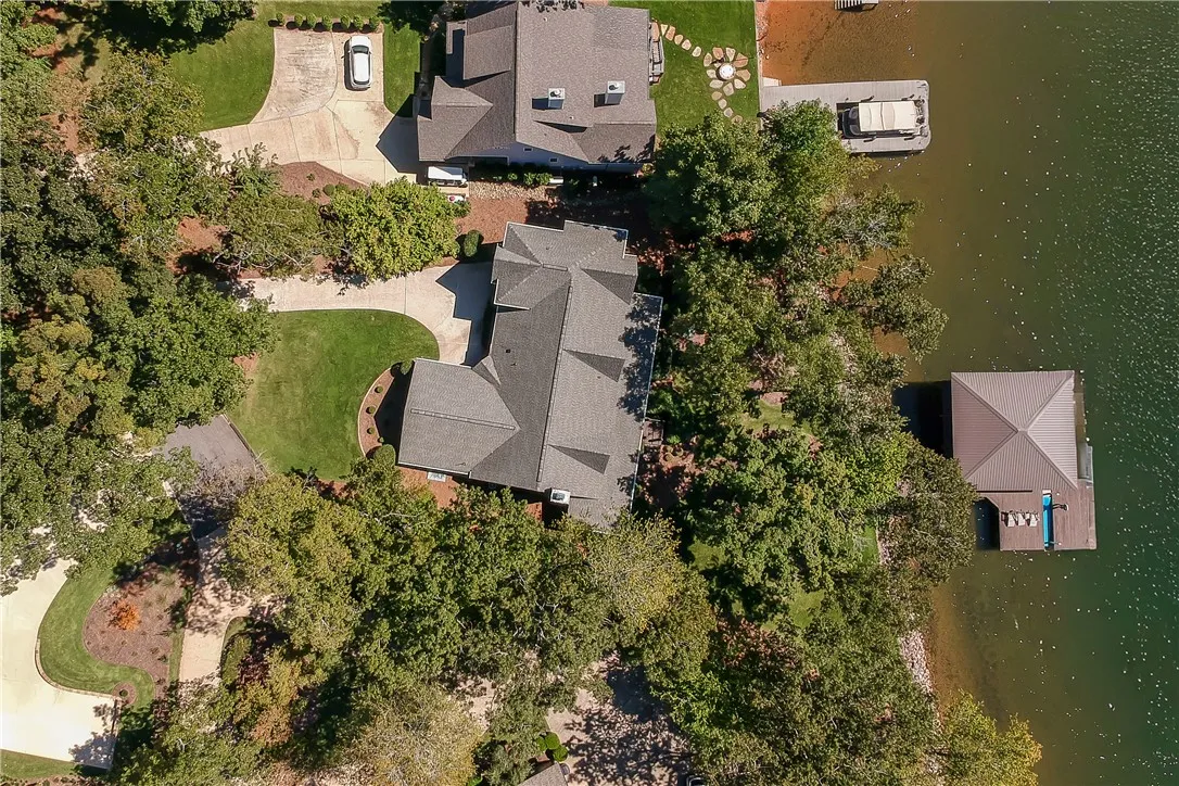 An aerial view showcases this waterfront property nestled among mature trees with a private dock.