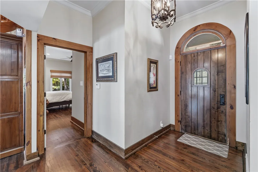 Rich wood trim frames a handsome arched entry door opening to warm hardwood floors.