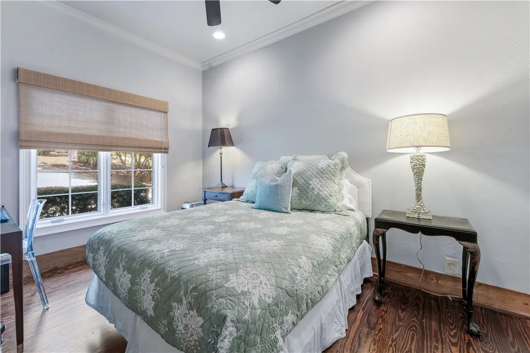 Rich hardwood floors and elegant crown molding define this restful bedroom space.