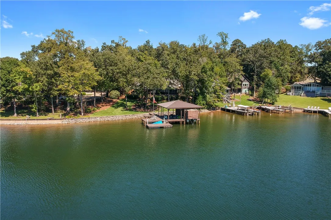 Lush mature trees line the peaceful shoreline surrounding a private covered dock.