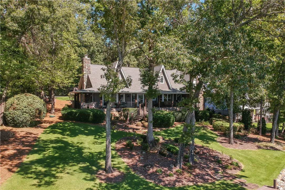Mature trees frame a charming multi-level residence set against a manicured sloping lawn.