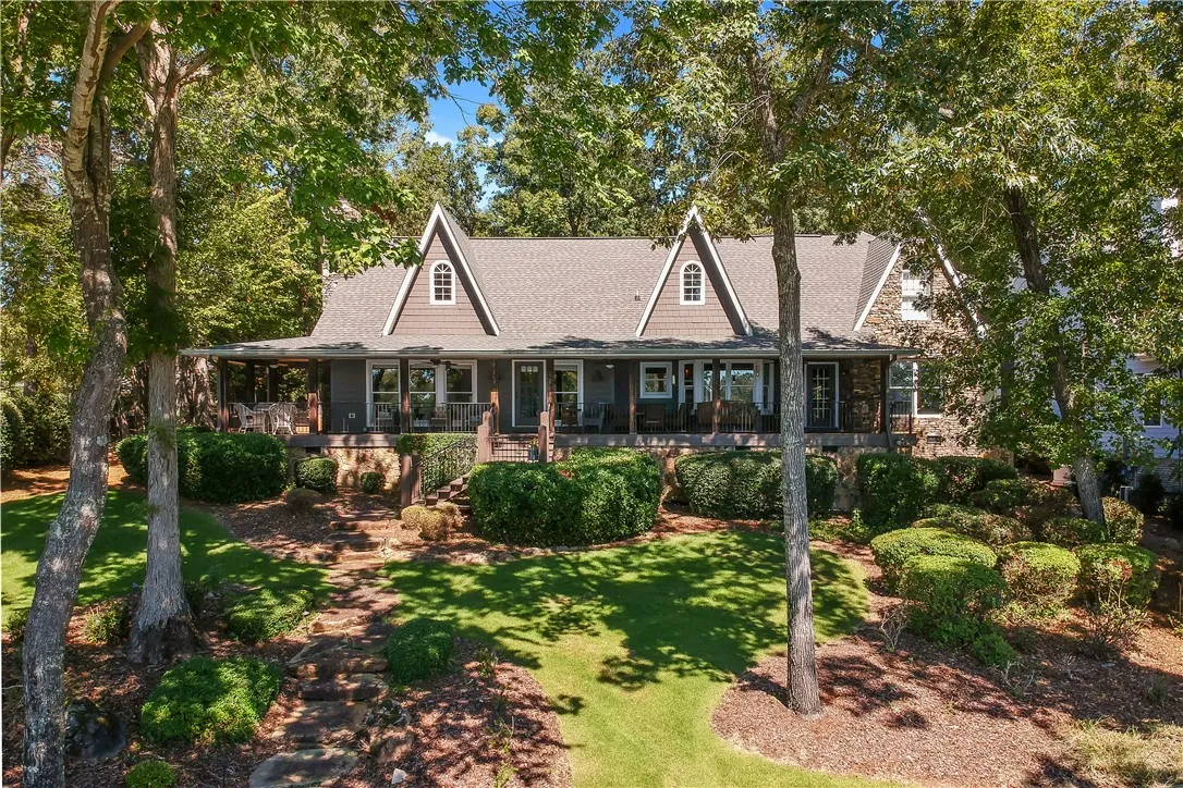 Mature trees frame a charming multi-gabled home fronted by a wide, welcoming porch.