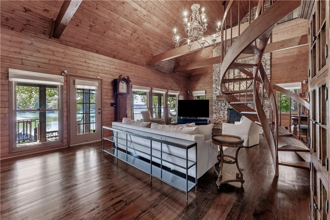 Rich wood plank ceilings and a spiral staircase anchor this magnificent waterfront living space.