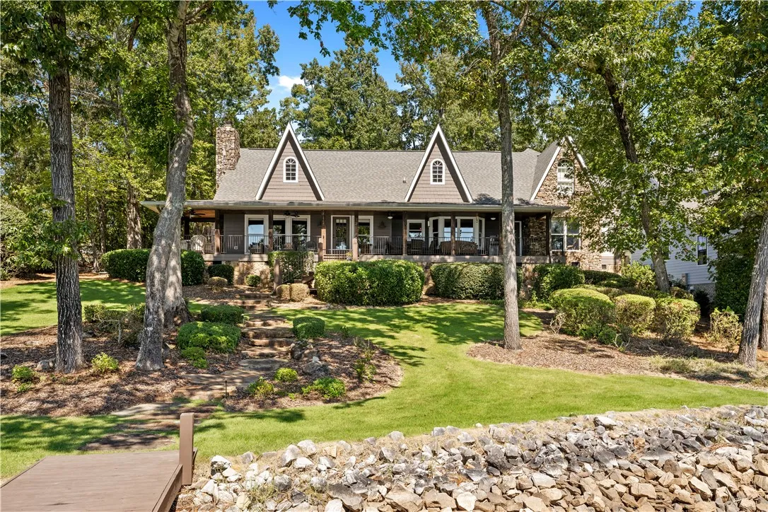 Mature trees frame a charming multi-gabled facade overlooking a landscaped lawn and stone path.