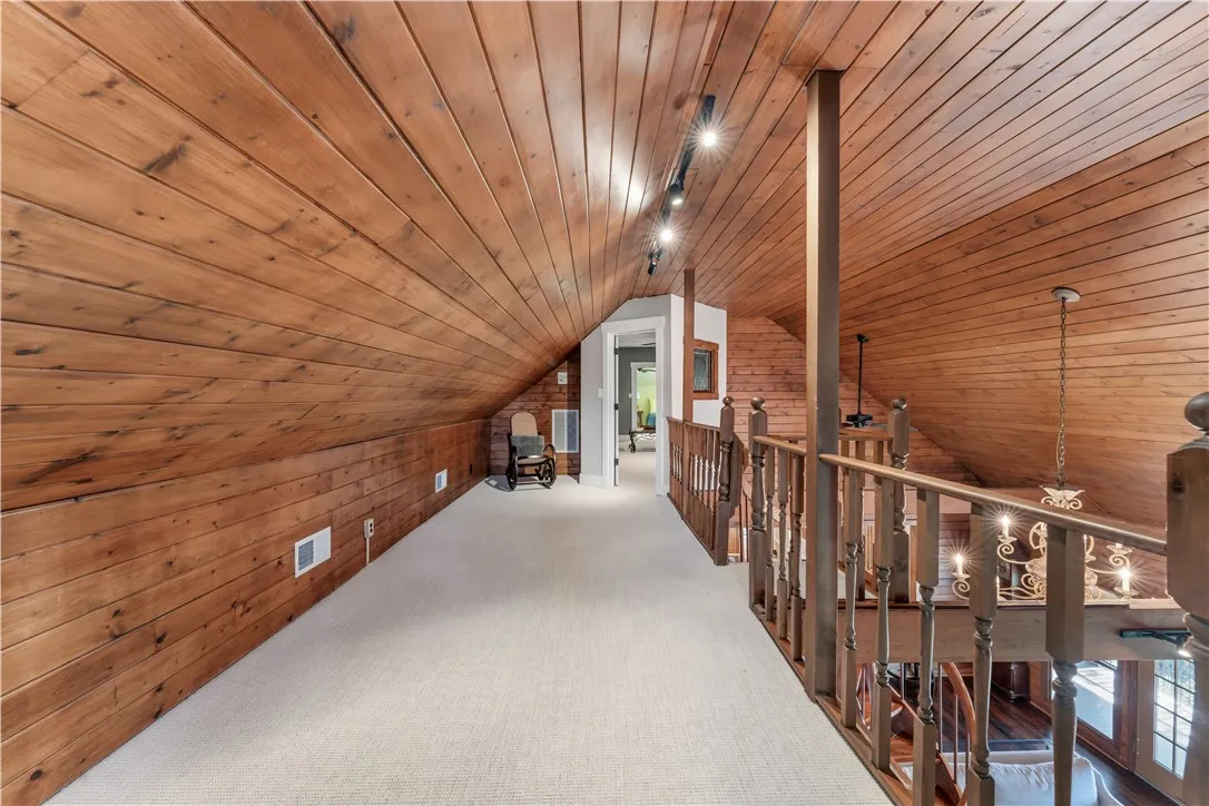 Rich wood planking wraps the vaulted ceilings and walls of this open loft hallway.