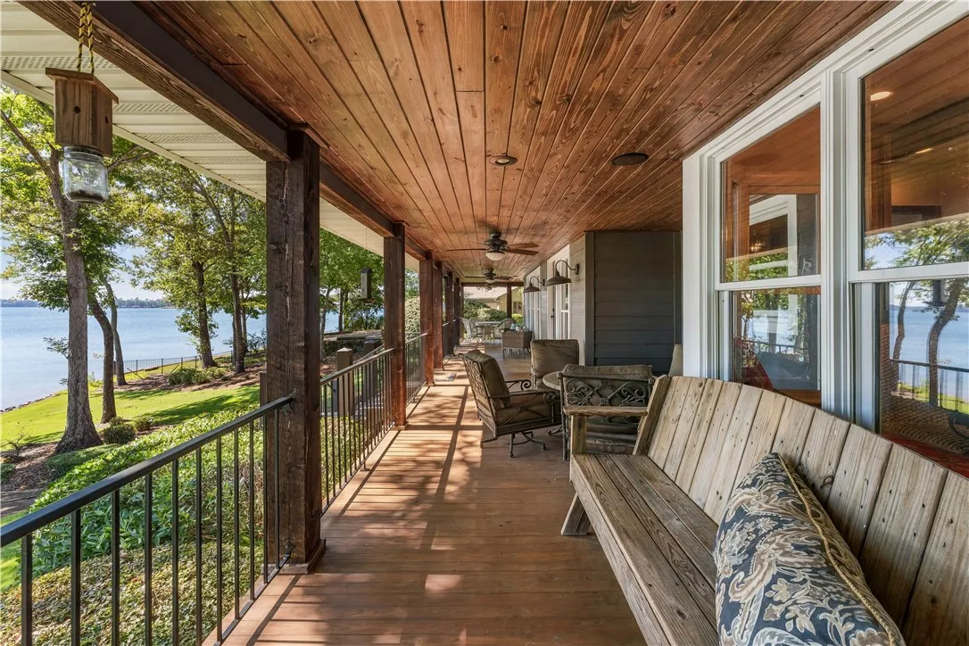 A spacious wood-paneled veranda provides a shaded vantage point overlooking peaceful lakeside views.