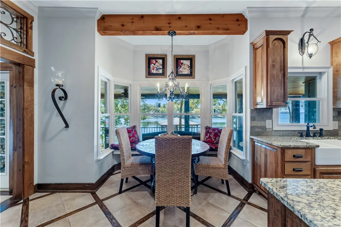 A sunny dining alcove features warm wood beams and views of the water through large windows.