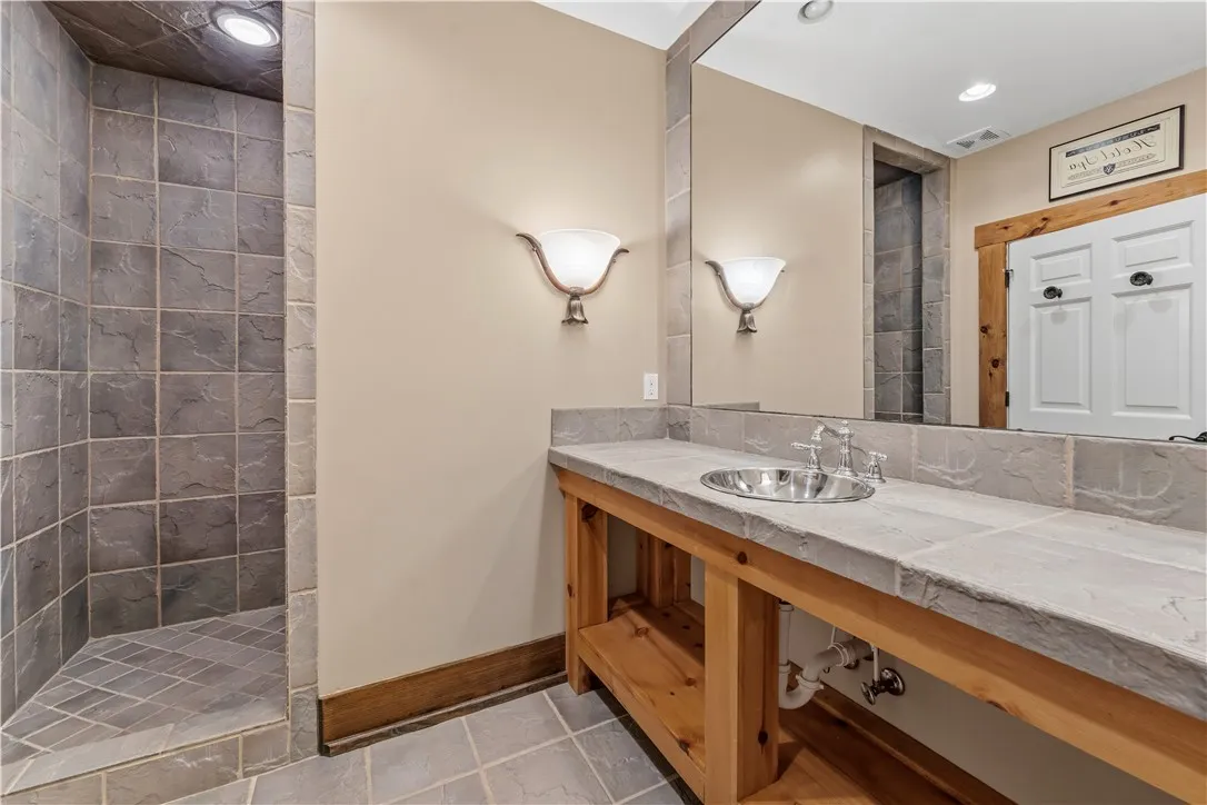 Natural stone surfaces and warm wood accents define this rustic bathroom design.