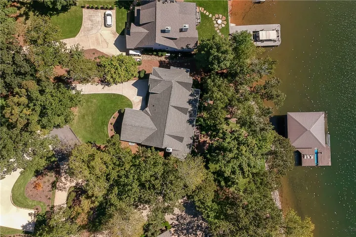 An aerial view showcases this waterfront property nestled among mature trees with a private dock.
