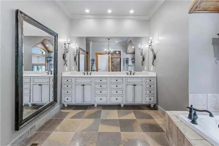 Ornate tile flooring runs beneath a large double vanity highlighted by classic crown molding.