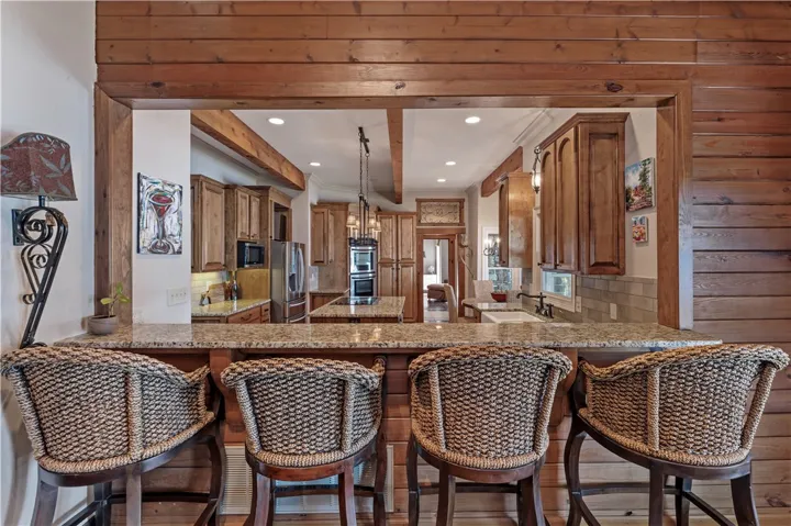 Rich wood paneling frames a raised granite breakfast bar overlooking the central kitchen​​‌​​​​‌​​‌‌​‌‌​​​‌‌​‌​‌​‌​​​‌​​ workspace.