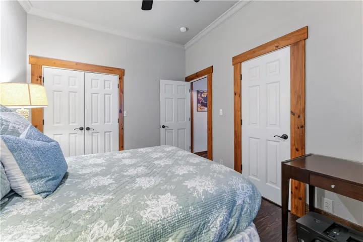 Rich wood trim frames the doorways in this bedroom featuring hardwood flooring and crown molding.