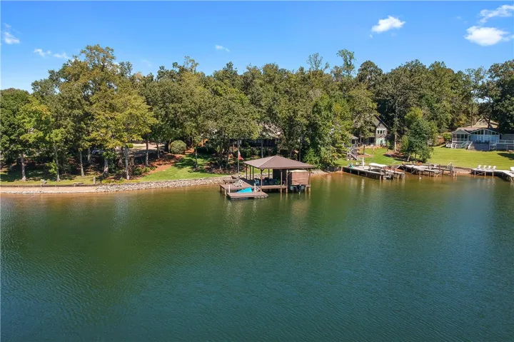 Lush mature trees line the peaceful shoreline surrounding a private covered dock.