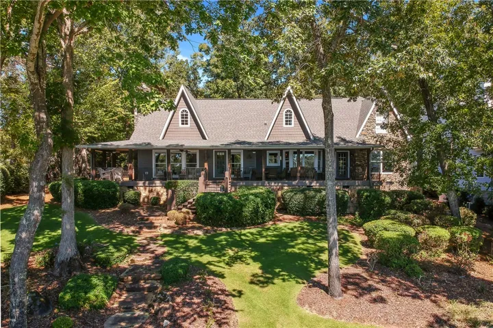 Mature trees frame a charming multi-gabled home fronted by a wide, welcoming porch.