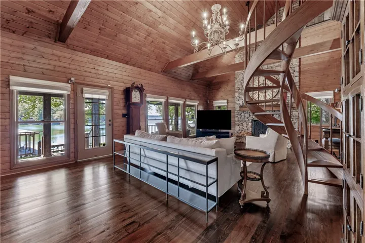 Rich wood plank ceilings and a spiral staircase anchor this magnificent waterfront living space.