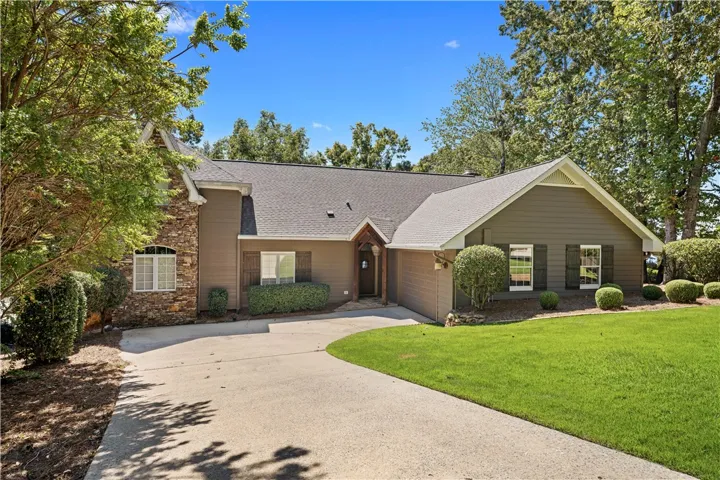 A spacious concrete driveway leads toward a classic multi-level residence nestled among mature trees.