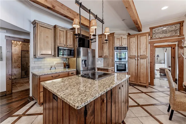 Exposed ceiling beams and rich granite countertops bring natural character to this custom kitchen.