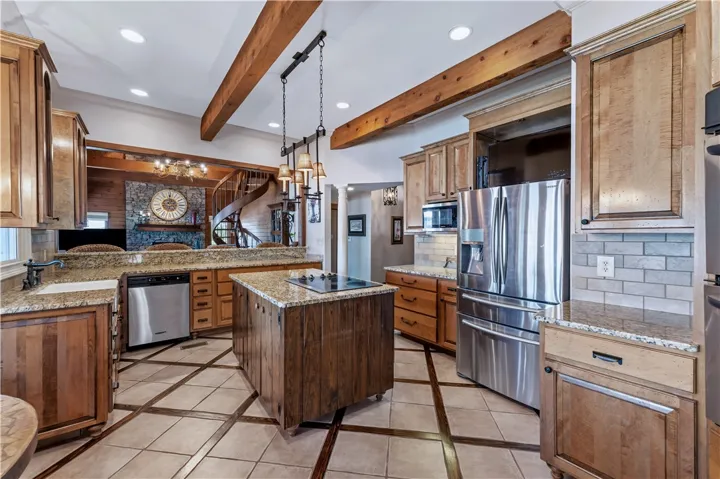Rich wood cabinetry and exposed ceiling beams create a warm, inviting atmosphere in this kitchen.