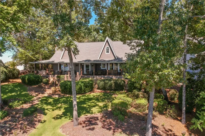 Mature trees frame a welcoming porch running along the front of this multi-level home.