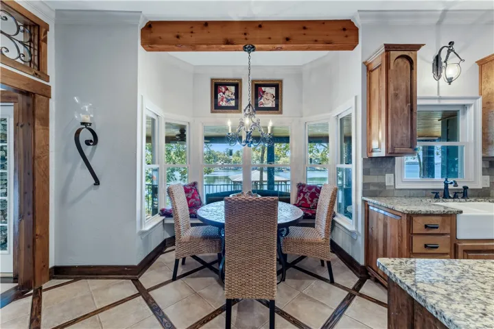 A sunny dining alcove features warm wood beams and views of the water through large windows.