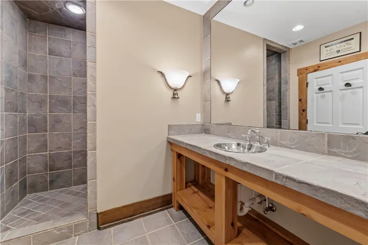 Natural stone surfaces and warm wood accents define this rustic bathroom design.