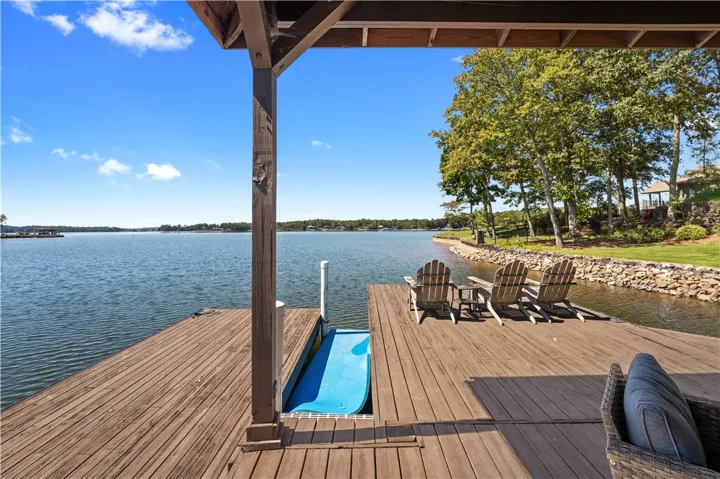 A spacious wooden dock overlooks the expansive water under clear blue skies.
