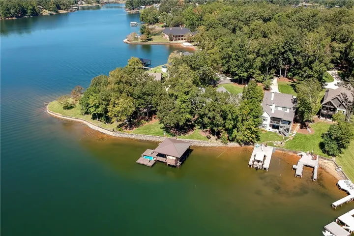 Mature trees frame this lakefront property featuring a private covered dock along the calm shoreline.