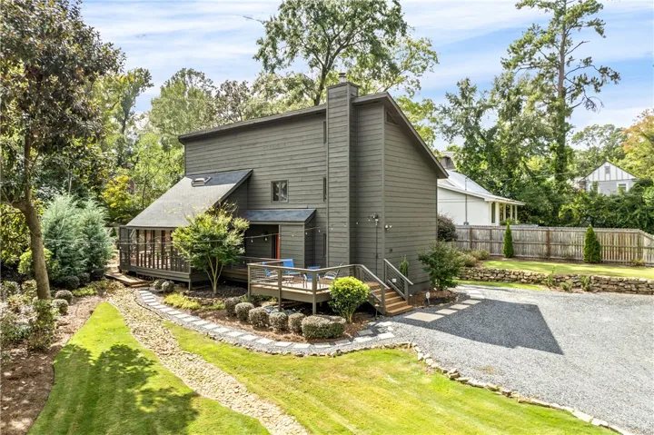 Mature trees frame a modern multi-level residence featuring wood siding and custom decking.
