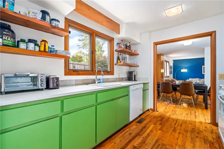 Rich hardwood flooring anchors this kitchen featuring open wood shelving and abundant natural light.