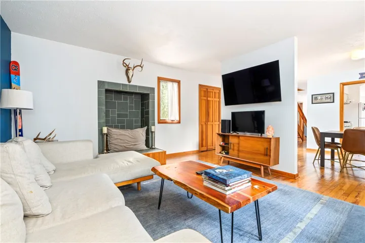 Warm wood floors and an open layout connect the living area to the adjacent dining room.