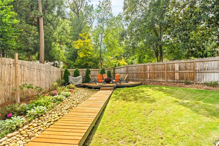 A wooden boardwalk meanders through a lush lawn toward a private raised deck.