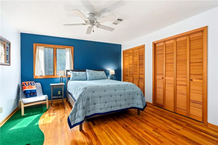 Gleaming hardwood floors and classic louvered closet doors define this comfortable bedroom space.