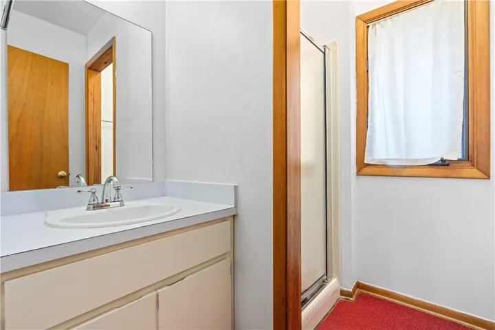 A classic bathroom featuring wood trim, a single vanity, and a glass-enclosed shower.